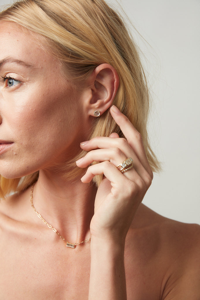woman wearing gold basket setting rose cut diamond stud alongside other gold jewelry