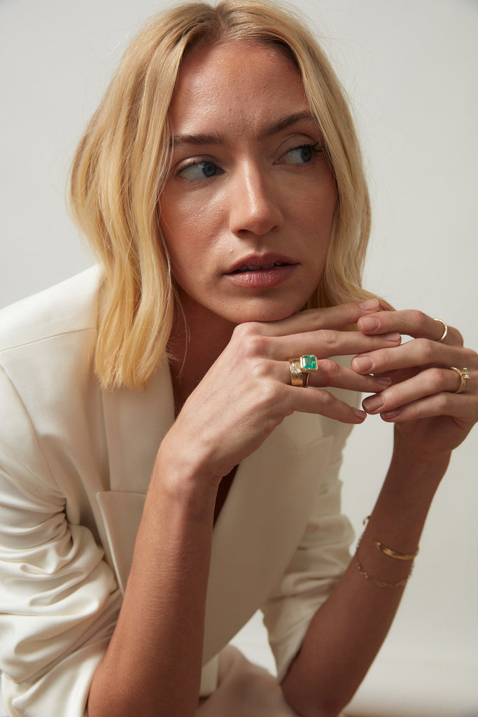 woman wearing Open Bottom Cathedral Bezel set colombian emerald ring with a gold soft knife edge band