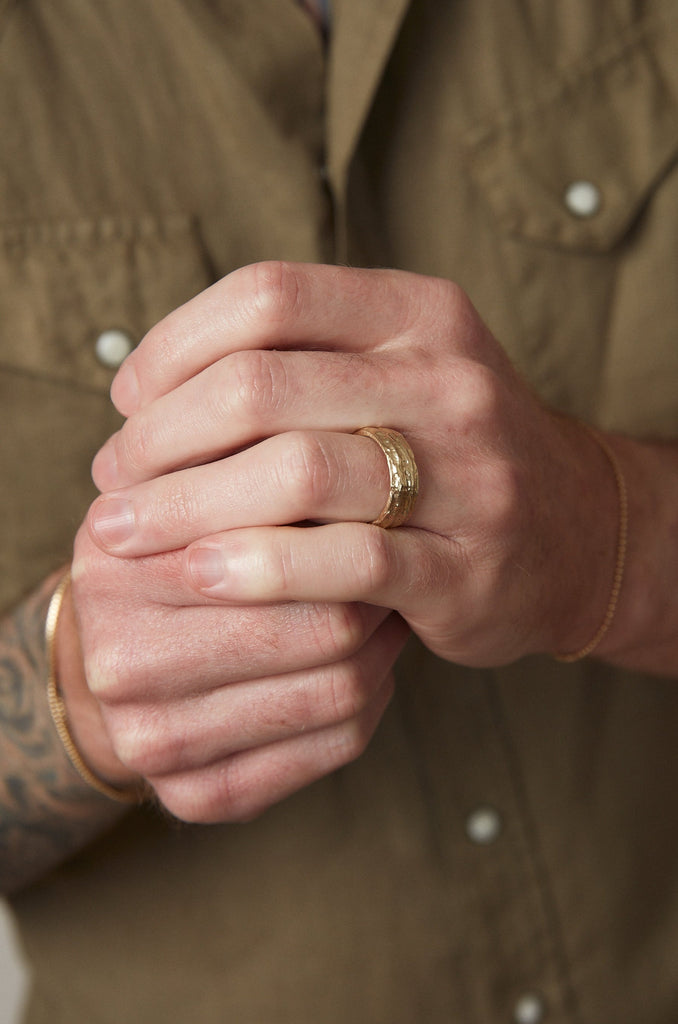 close up of man's hand wearing textured gold man