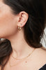 close up of woman wearing free form gold stud earrings with round white diamond alongside other gold earrings