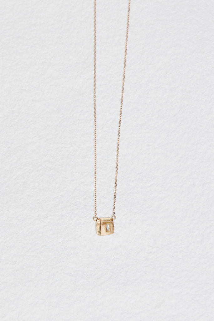 gold necklace with gold square design containing baguette white diamond