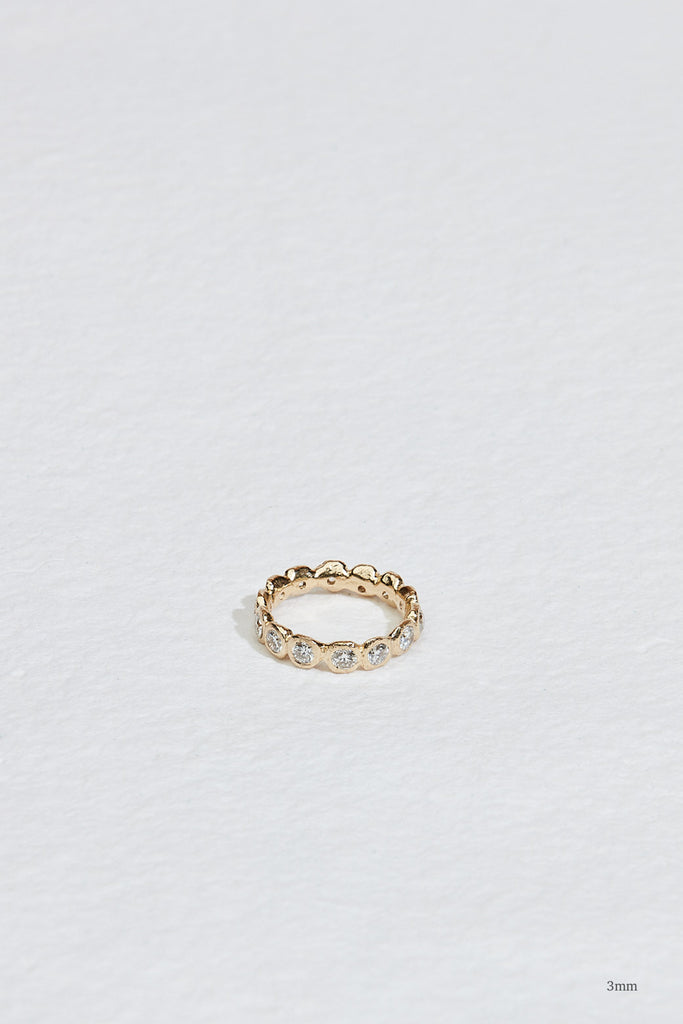 gold eternity band with bezel set round diamonds