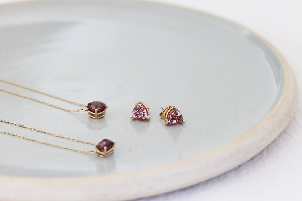 gold necklace with asscher cut malaya garnet alongside other garnet jewelry