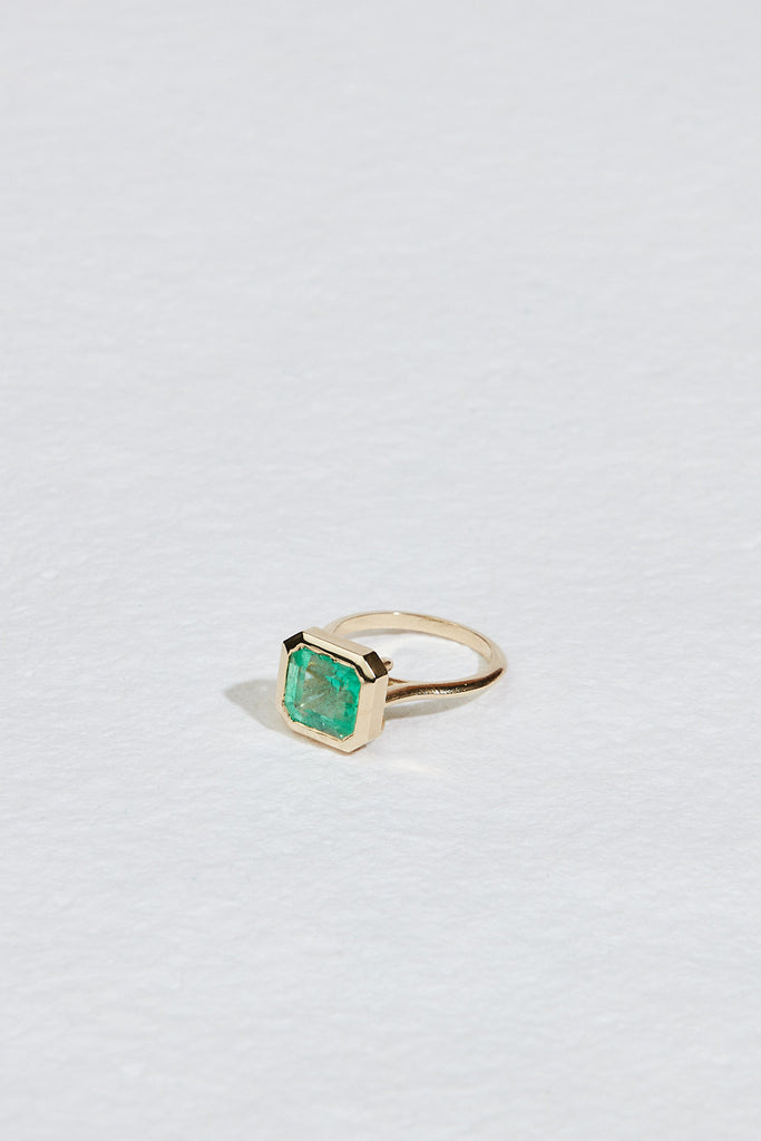 side view of Open Bottom Cathedral Bezel set colombian emerald ring with a gold soft knife edge band