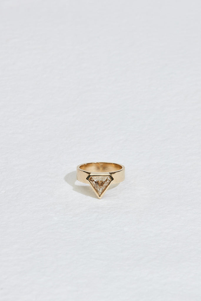 close up of gold band with bezel set shield shaped yellow brown diamond