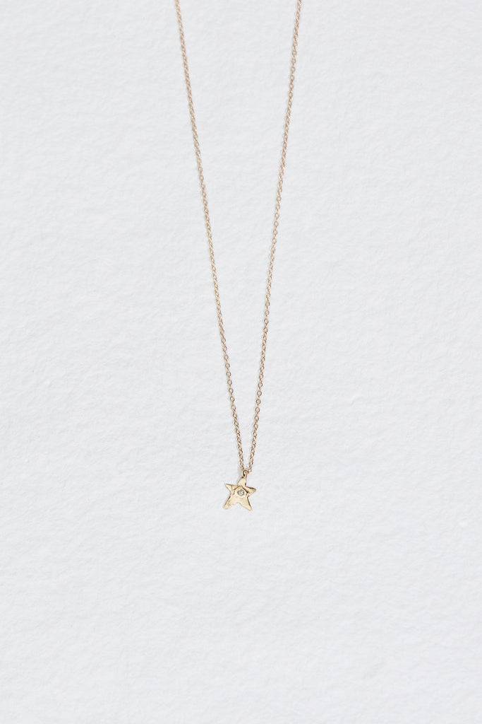 gold necklace and gold star with round white diamond