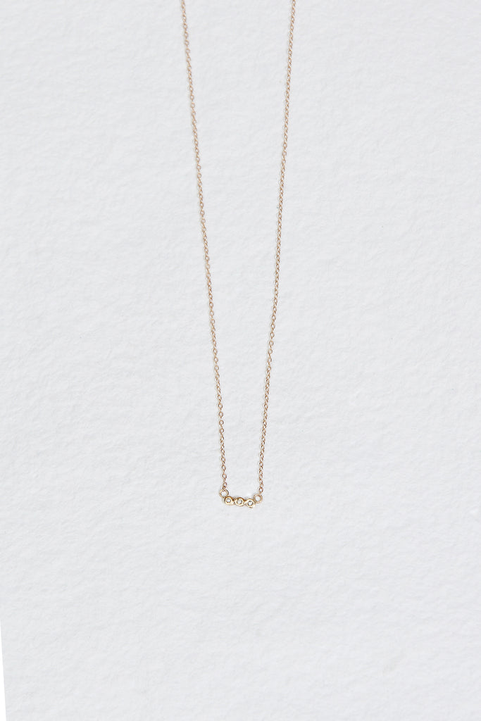gold necklace with three bezel set round white diamonds