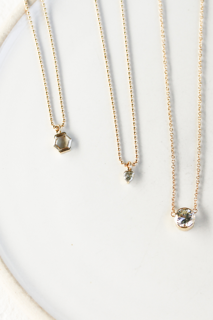 gold ball chain necklace with partial bezel set trillion salt and pepper diamond alongside other diamond necklaces