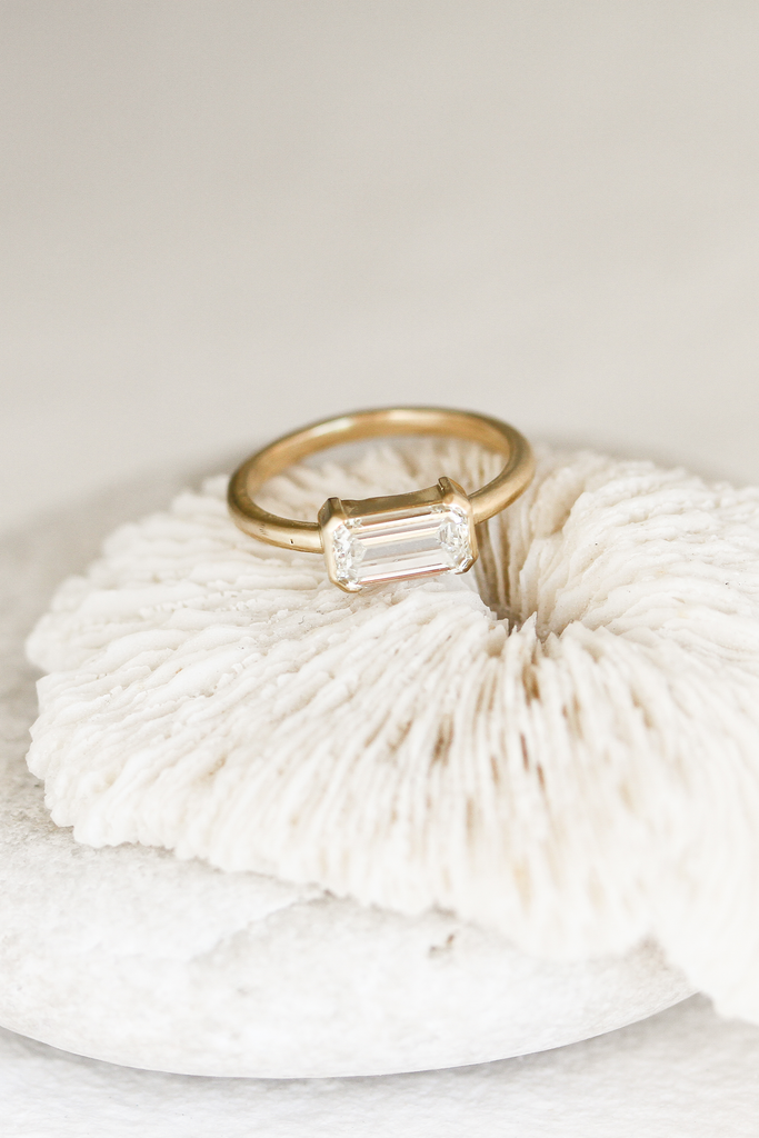 gold partial bezel emerald cut diamond ring