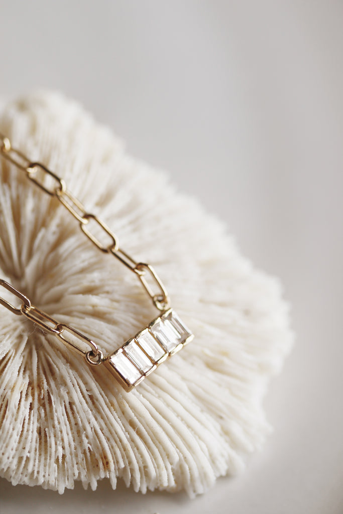 close up of gold cable chain necklace with 5 baguette diamonds
