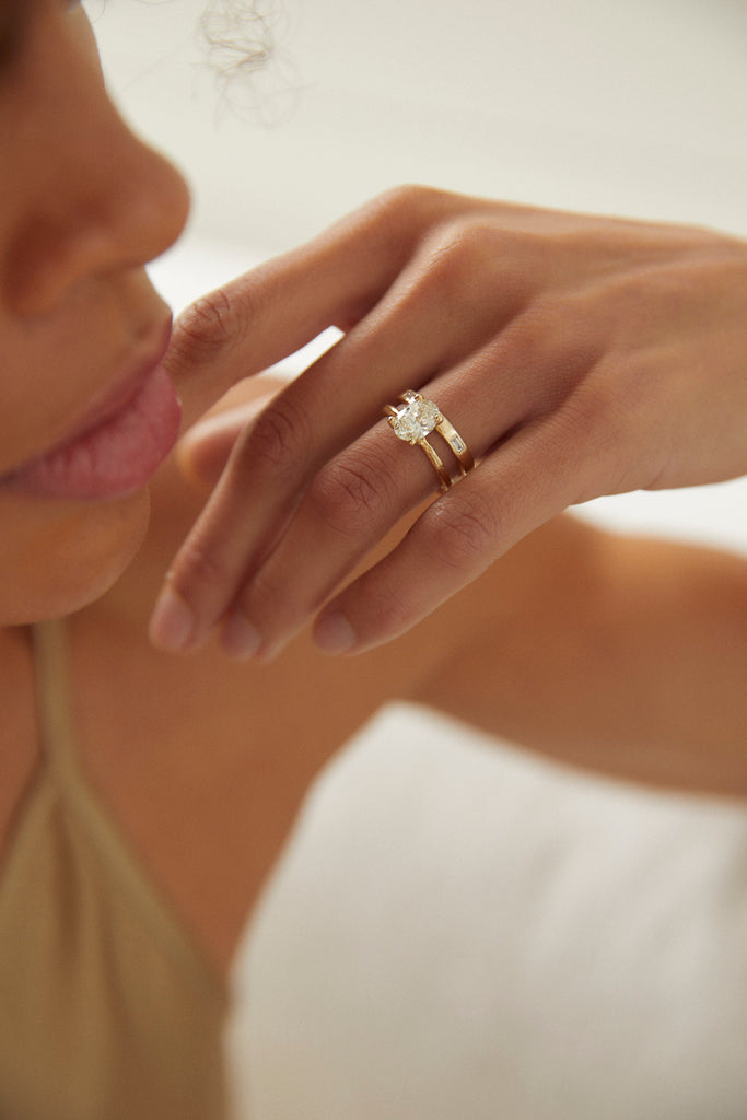 woman wearing yellow gold band with three baguette white diamonds alongside other ring