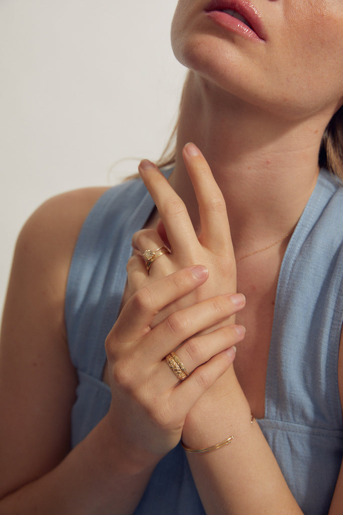 woman wearing gold ring with "BIG LOVE" engraved plate alongside other gold jewelry