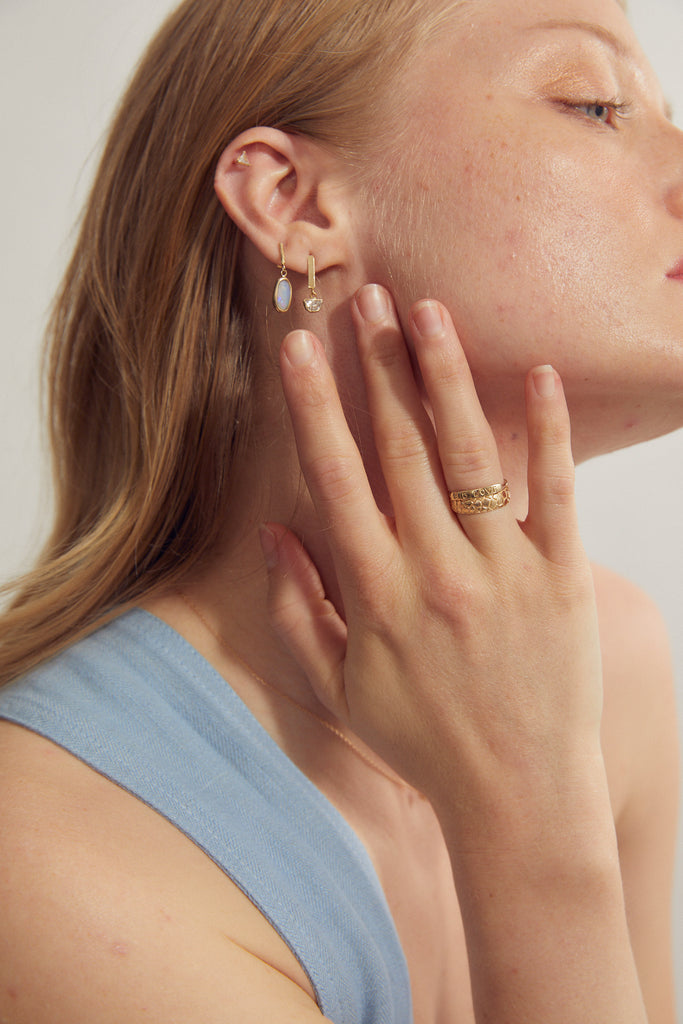 woman wearing gold ring with "BIG LOVE" engraved plate alongside other gold jewelry