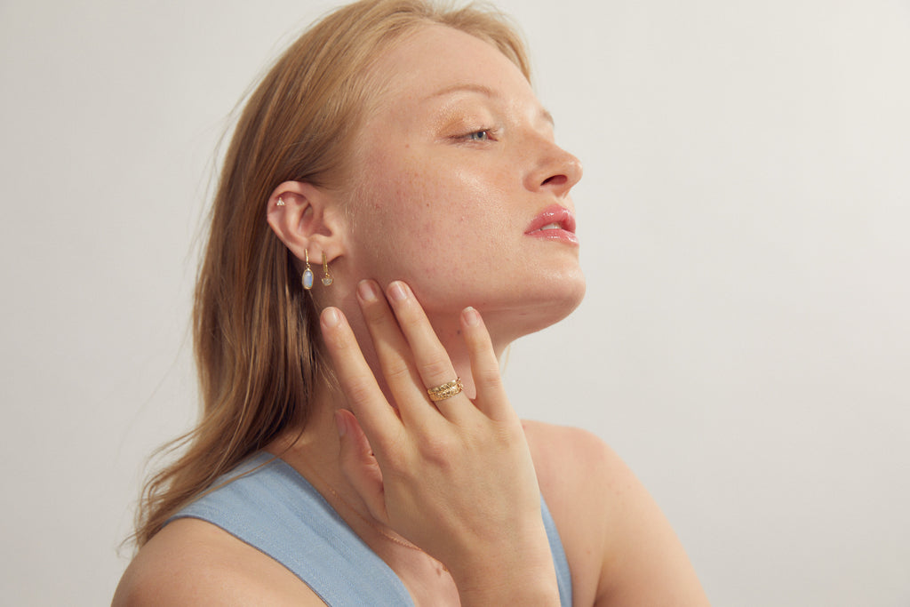 woman wearing gold ring with "BIG LOVE" engraved plate alongside other gold jewelry
