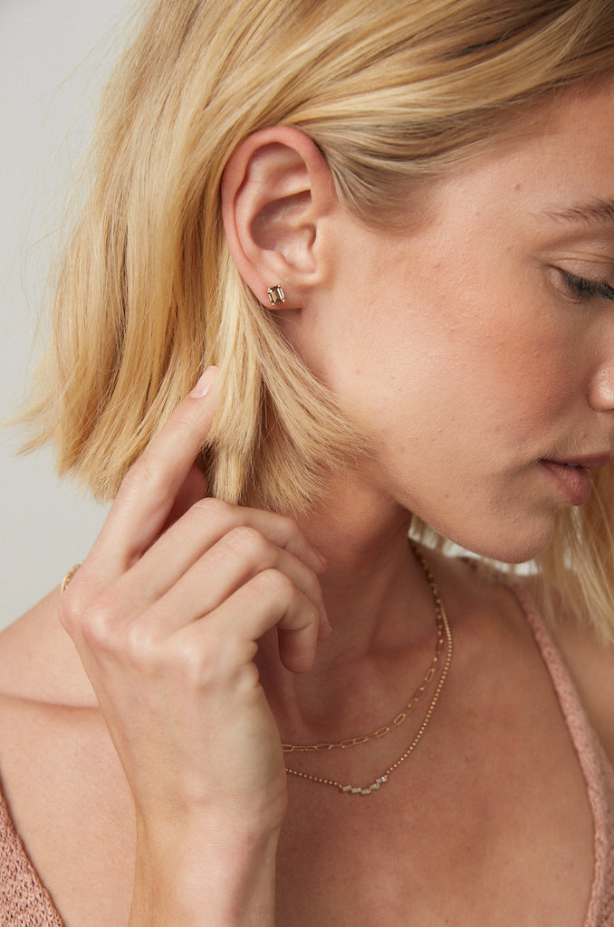 woman wearing emerald cut champagne diamond studs alongside other gold jewelry