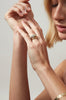 woman wearing gold ring with three bezel set round white diamonds alongside other gold jewelry