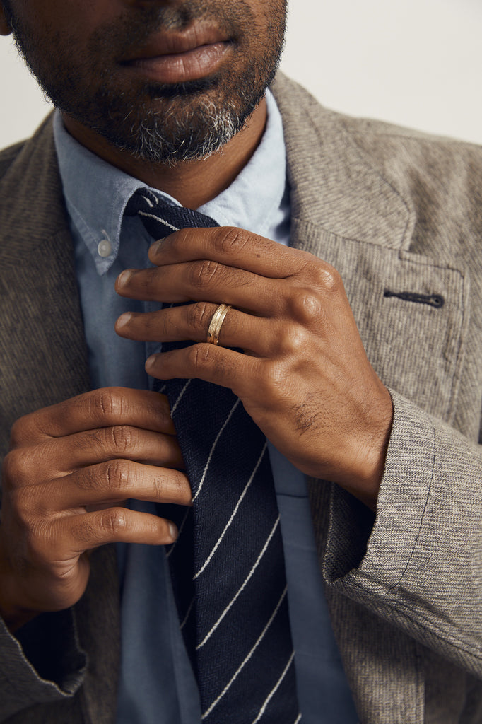 close up of man's hand wearing gold band with notched detail around center