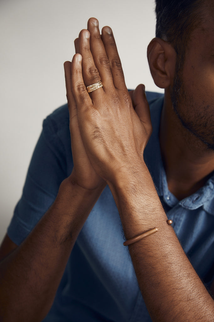 close up of man's hand wearing textured gold ring