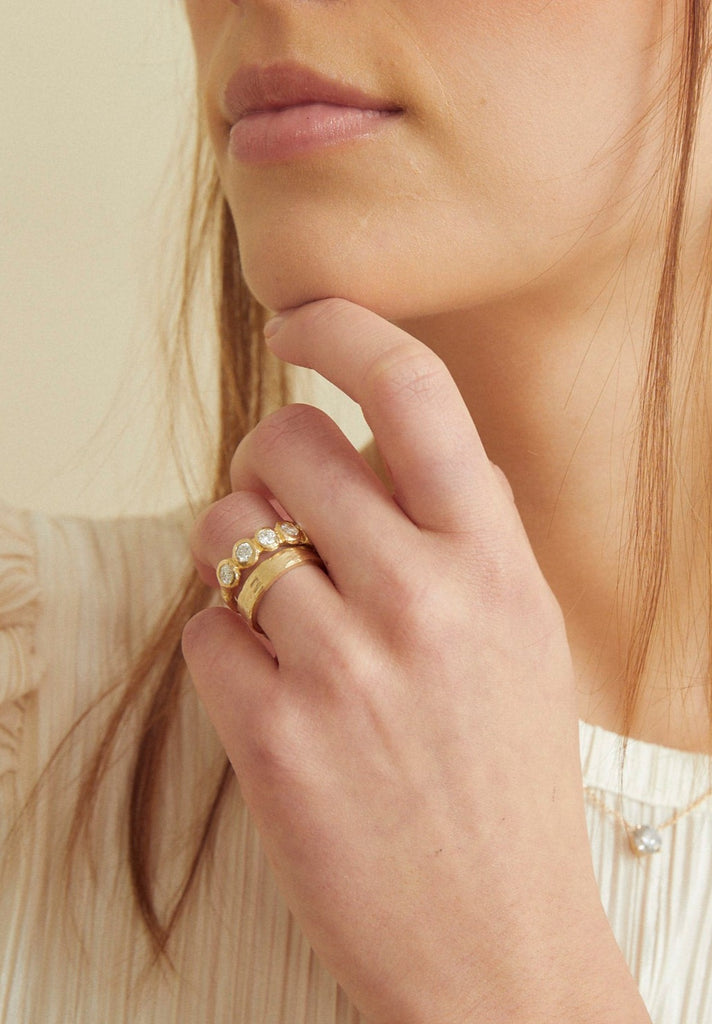 woman wearing gold band with six bezel set round diamonds alongside other gold band