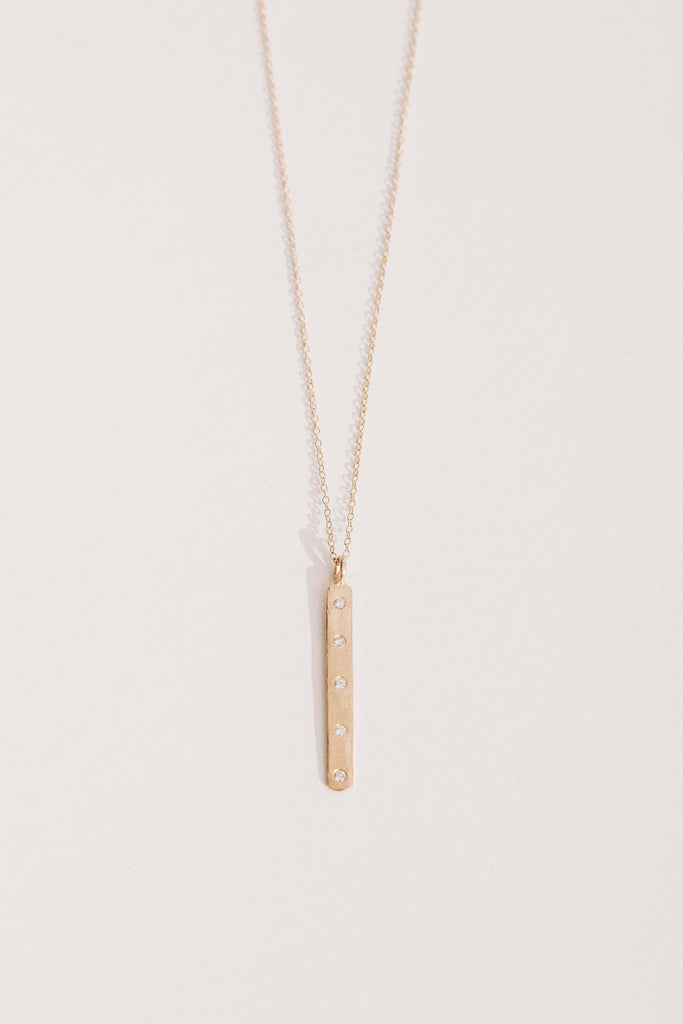 gold necklace with vertical gold bar studded with round white diamonds