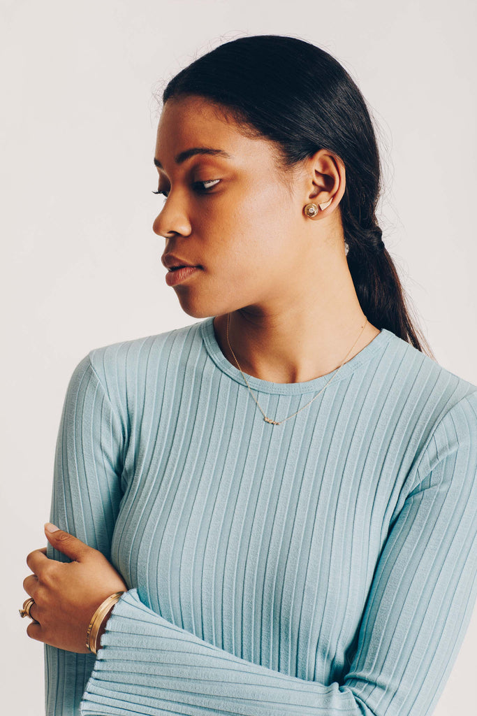 woman wearing gold disc stud with round white diamond alongside other gold jewelry