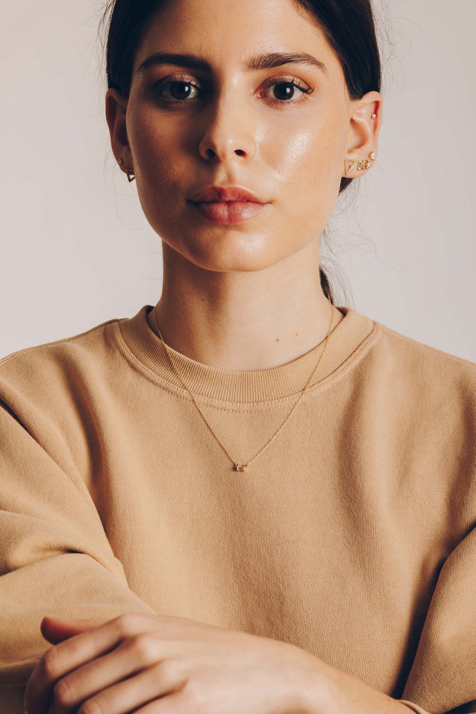 woman wearing gold necklace with white diamond baguette alongside other gold jewelry