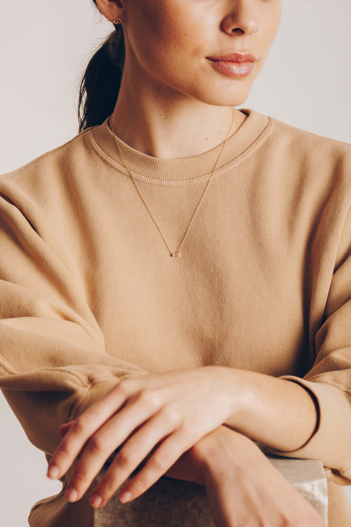 close up of woman wearing gold necklace with white diamond baguette