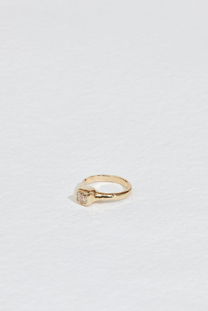 side view of gold ring with cushion cut bezel set white diamond