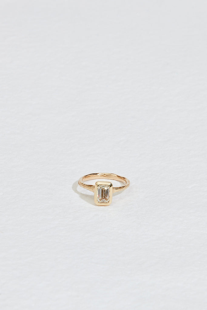 gold ring with bezel set emerald cut white diamond