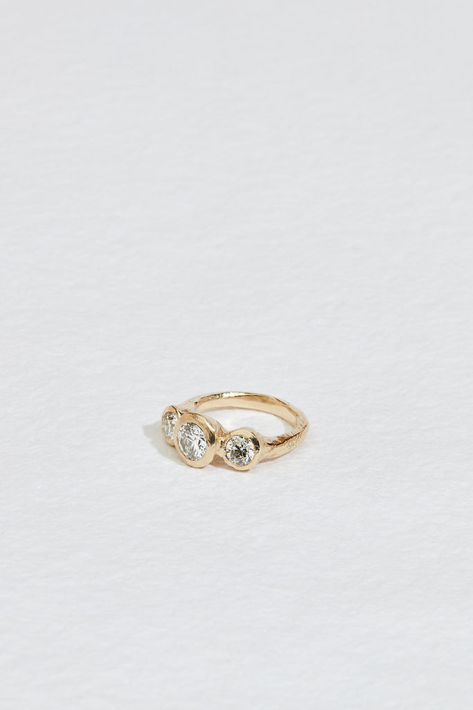 side view of gold ring with three bezel set round white diamonds