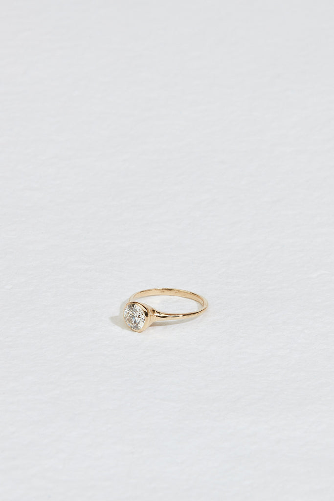 side view of gold ring with bezel set round white diamond