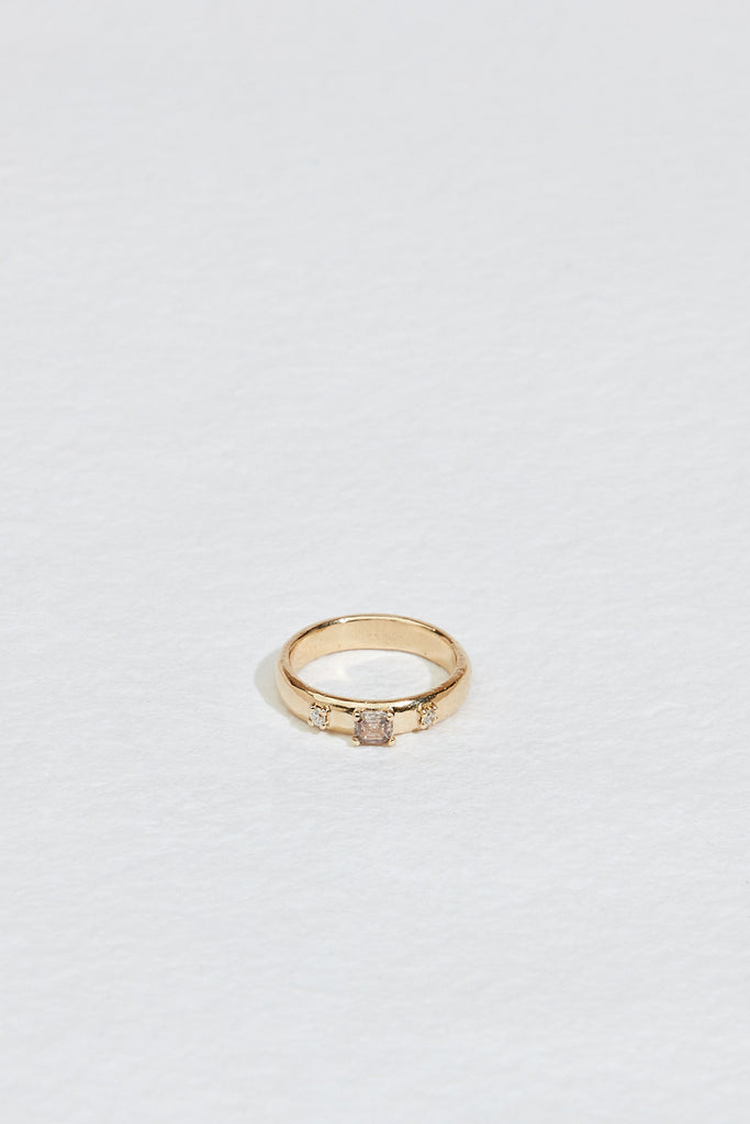 gold band with emerald cut champagne diamond and two round white diamonds