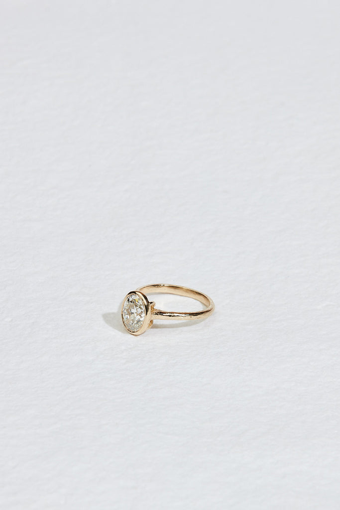 side view of gold ring with bezel set oval white diamond