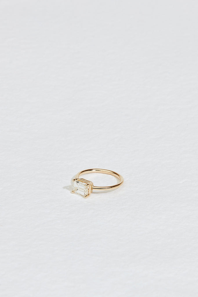 side view of gold four prong emerald cut white diamond ring