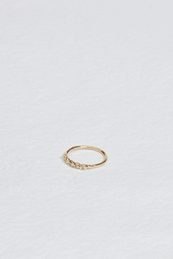 side view of gold ring with five bezel set round white diamonds