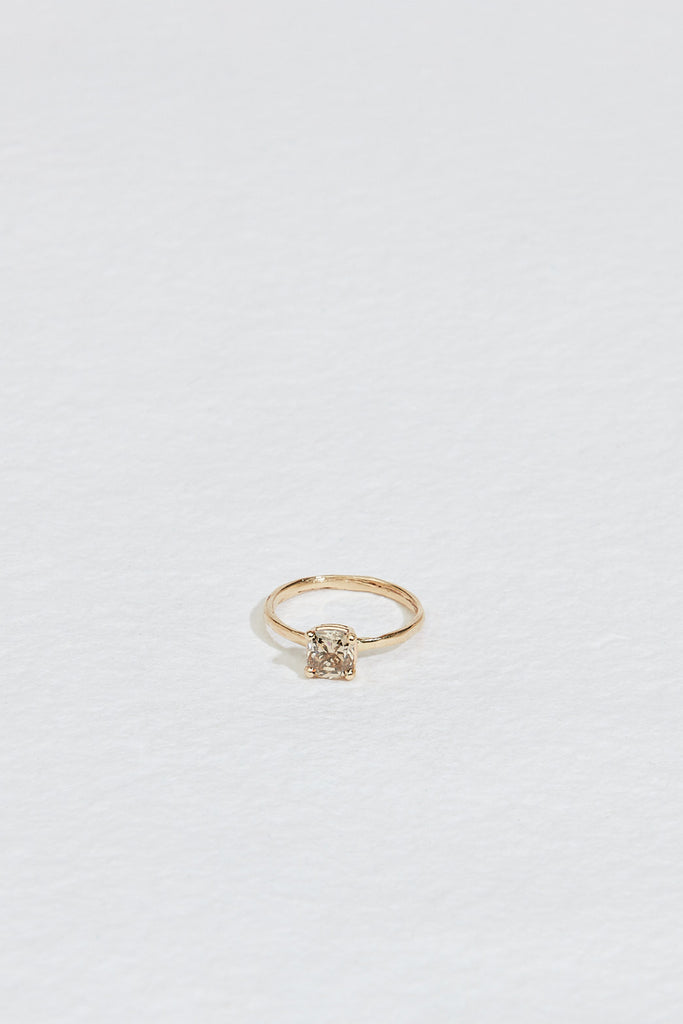 close up of four prong gold ring with cushion cut light champagne diamond