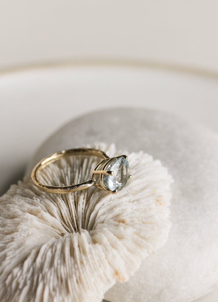 side view of gold four prong oval aquamarine ring with textured band