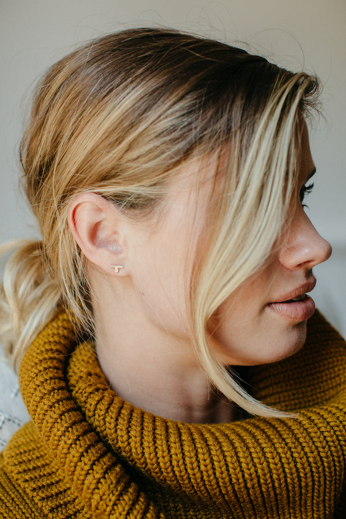 woman wearing gold stud with slate bar and off set bezel set diamond