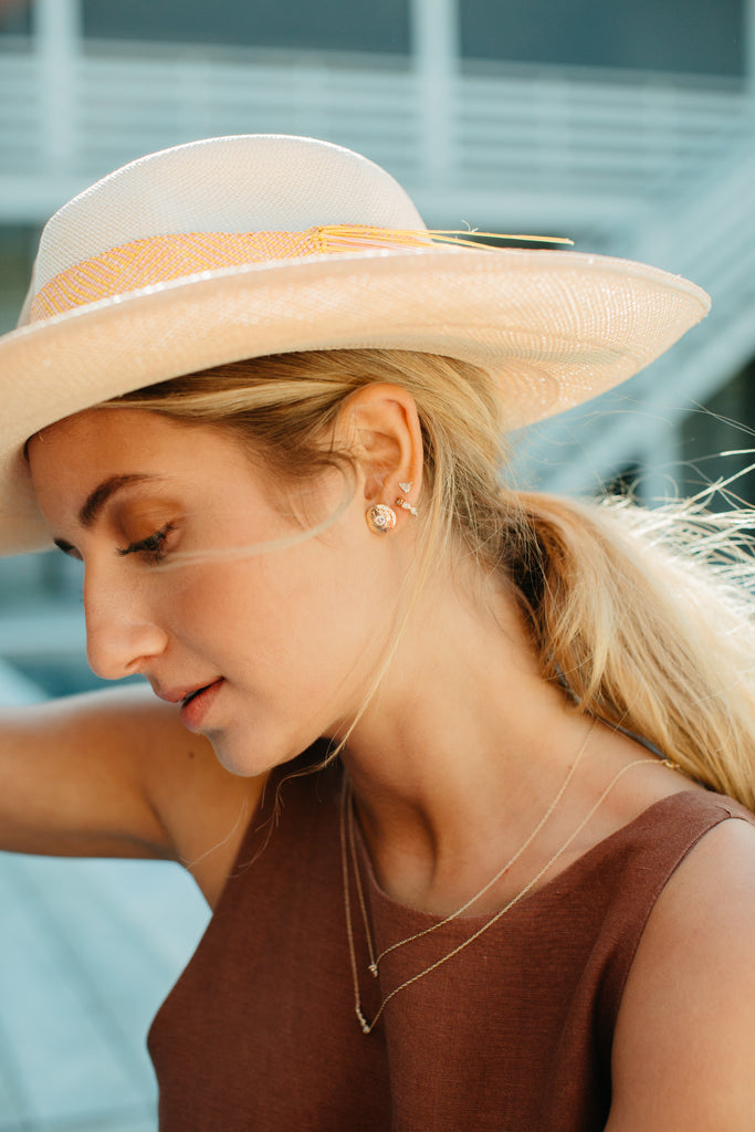 woman wearing gold disc stud with round white diamond alongside other gold jewelry