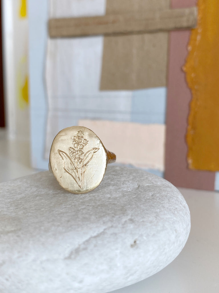 close up of gold signet ring with engraved flower