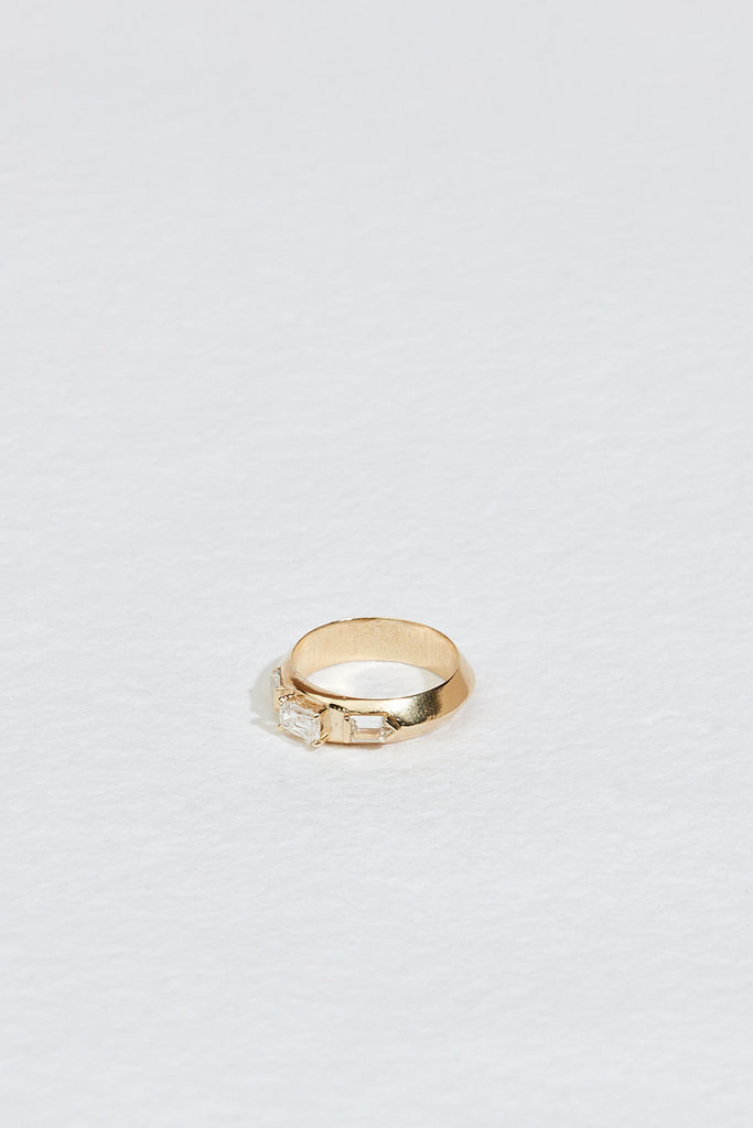 side view of gold knife edge band with two bullet cut white side diamonds and center round-cornered rectangular white ocean diamond