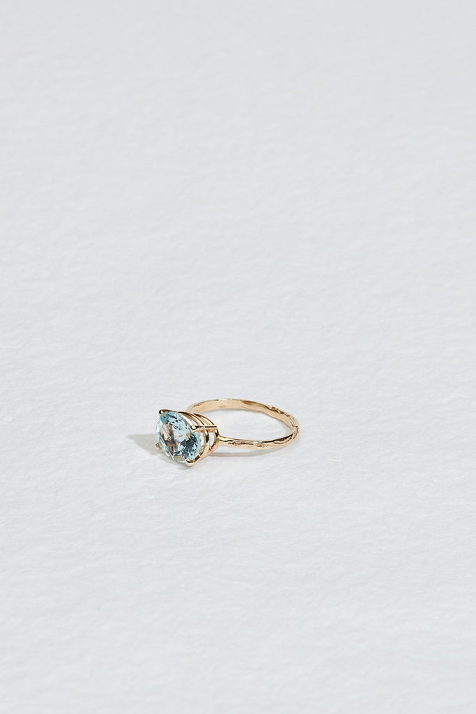 side view of gold four prong oval aquamarine ring with textured band