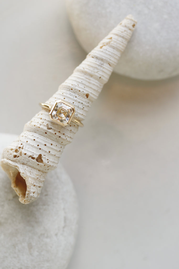 close up of gold ring with bezel set asscher cut white diamond