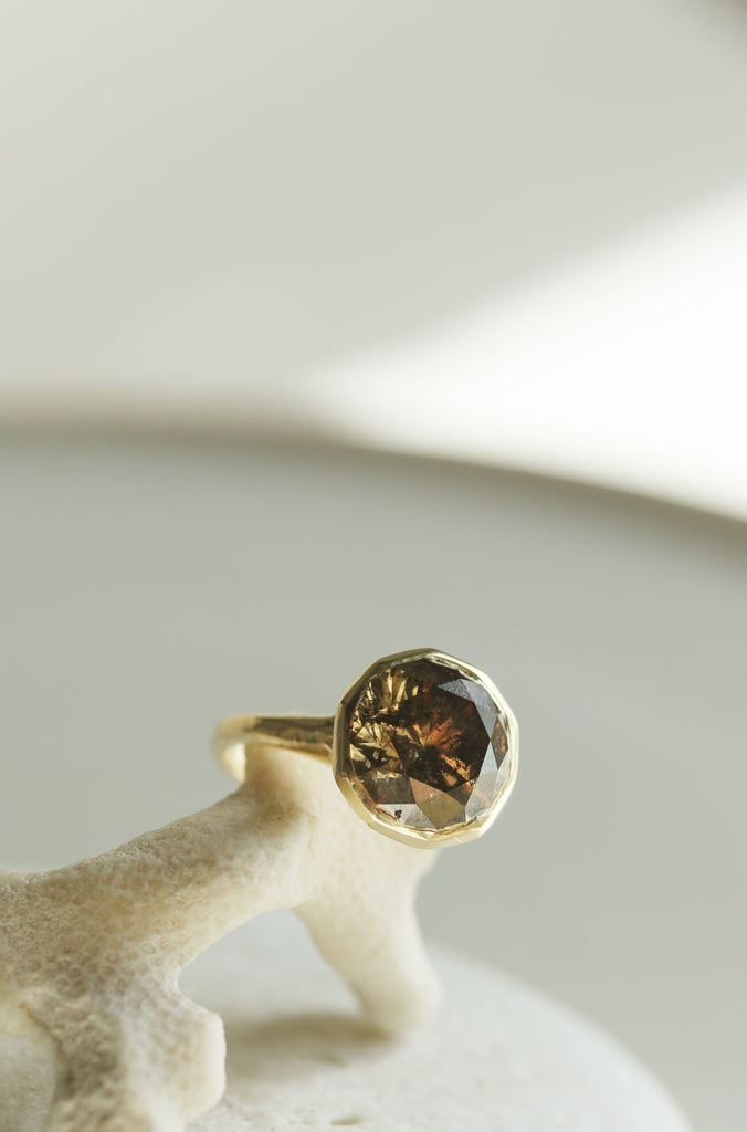 close up of gold ring with decagon bezel set round mocha diamond