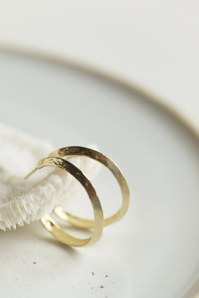close up side view of gold knife edge cut hoop earrings