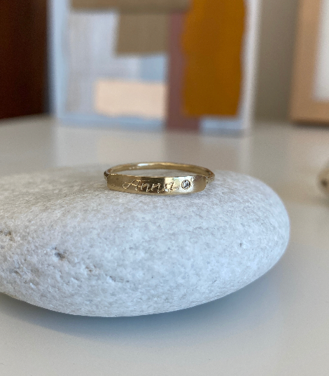 gold ring with hand engraved front plate and round white diamond