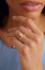close up of woman wearing gold oval and circle bezel set eternity band with round white diamonds alongside other gold jewelry