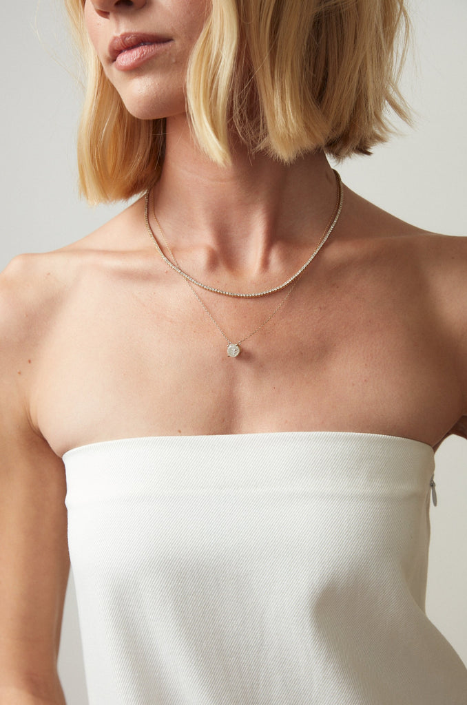 woman wearing gold necklace with round salt and pepper diamond with diamond line necklace