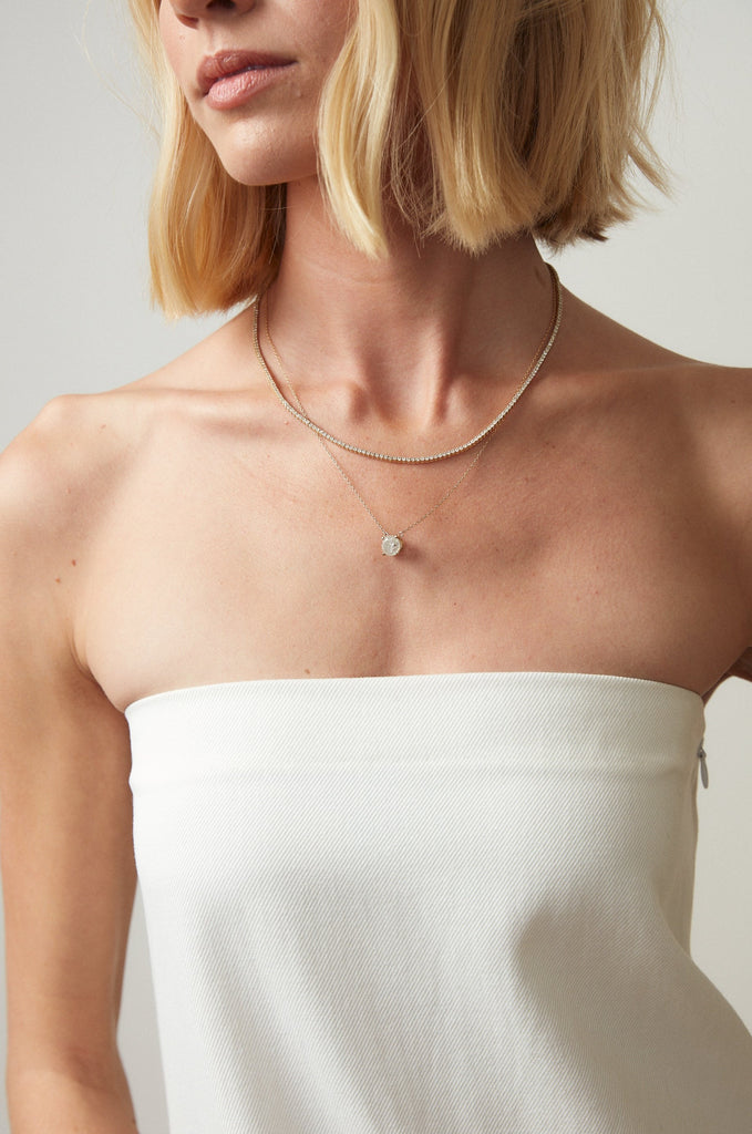 woman wearing diamond line necklace alongside another necklace