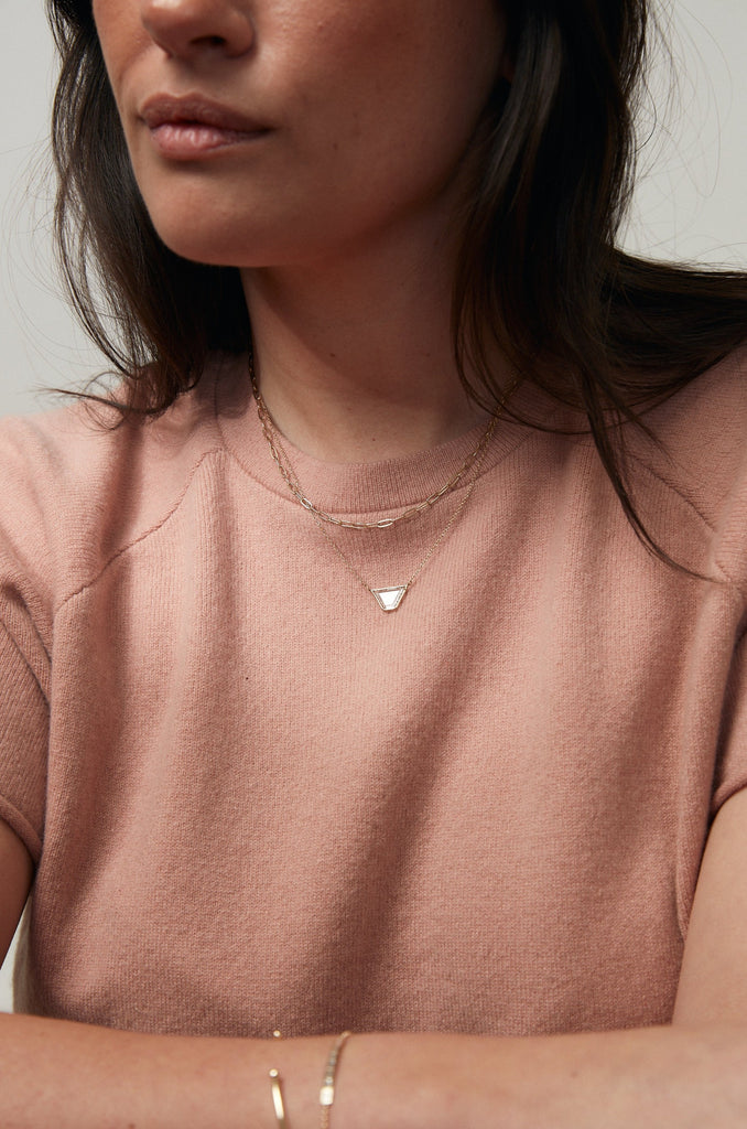 woman wearing gold necklace with trapezoid shaped diamond slice alongside gold cable link chain